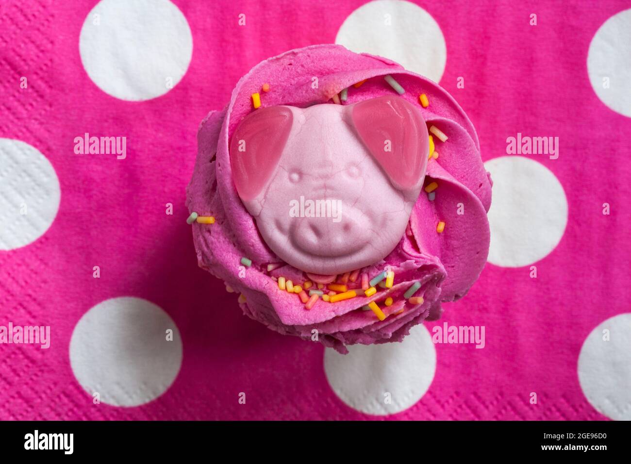 Percy Pig party cupcake cake from M&S set on pink polka dot serviette napkin Stock Photo