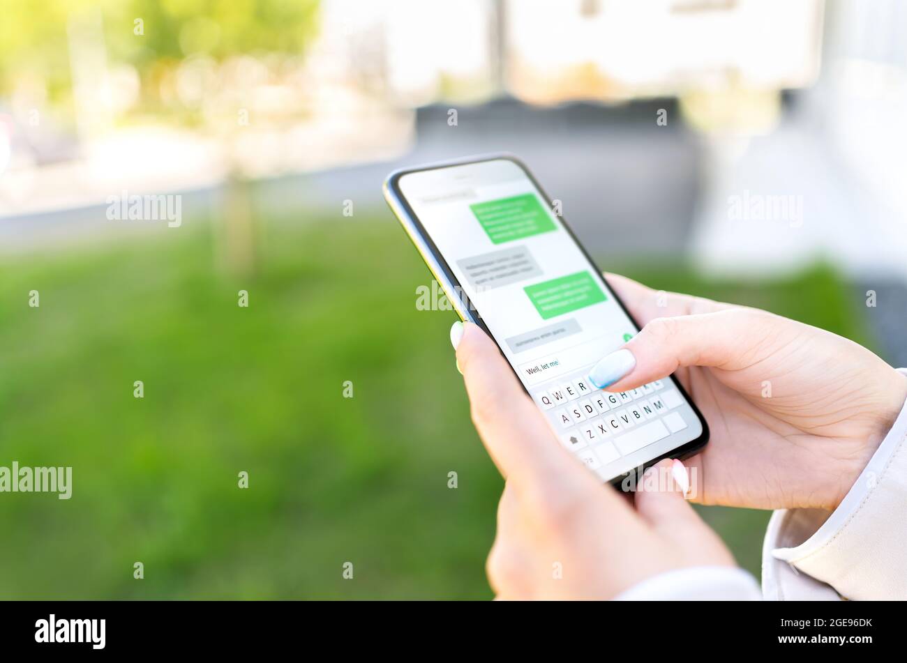 Texting sms with phone in city outdoor park. Woman sending text message with cellphone. Chatting on instant messaging app. Person using smartphone. Stock Photo