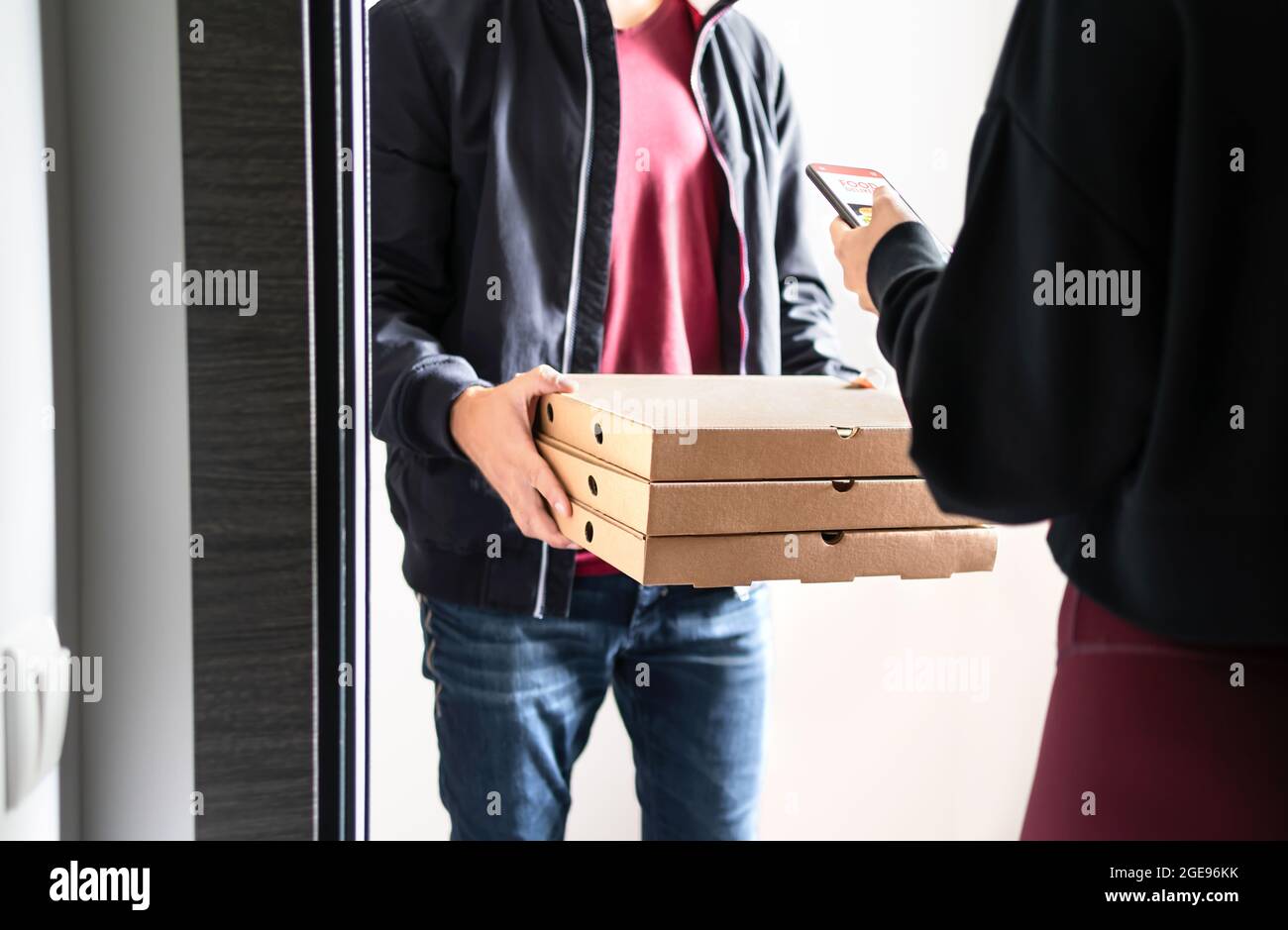 Pizza delivery to door. Online order with phone. Customer using smartphone mobile app to pay, tip or give rating and review. Home deliverer. Stock Photo