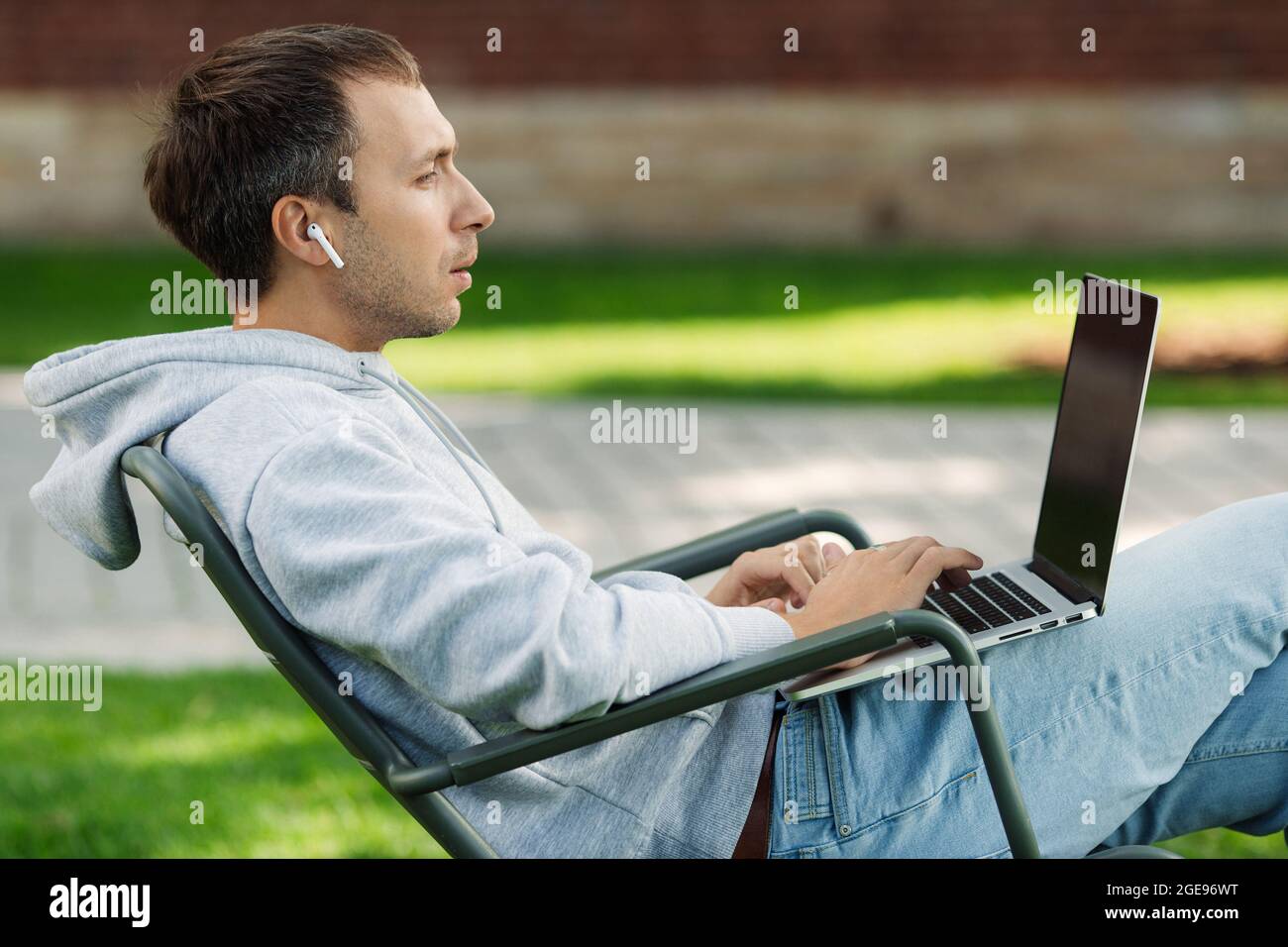 Blogger male work on computer in public park processes video for social ...