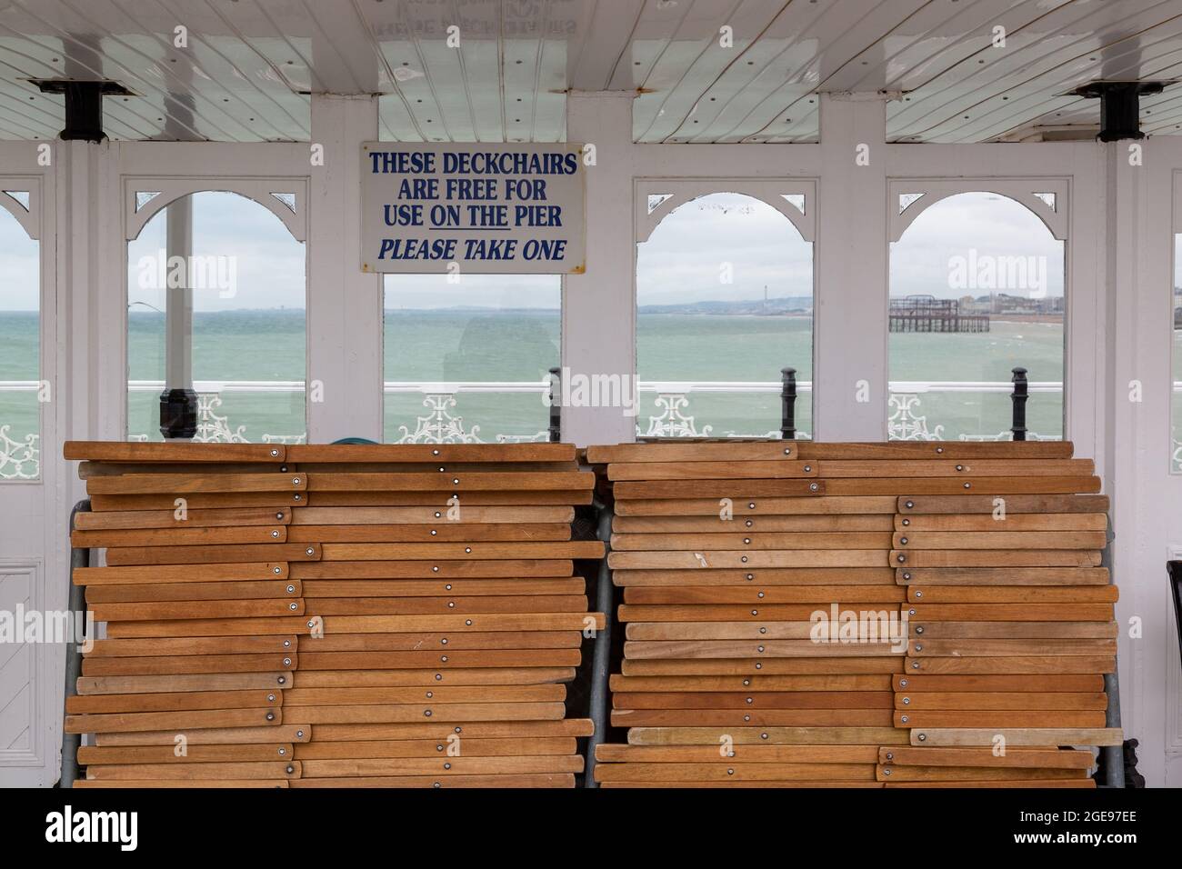 A sign above deck chairs on a pier reading that deckchairs are free to use on the pier at the British seaside Stock Photo