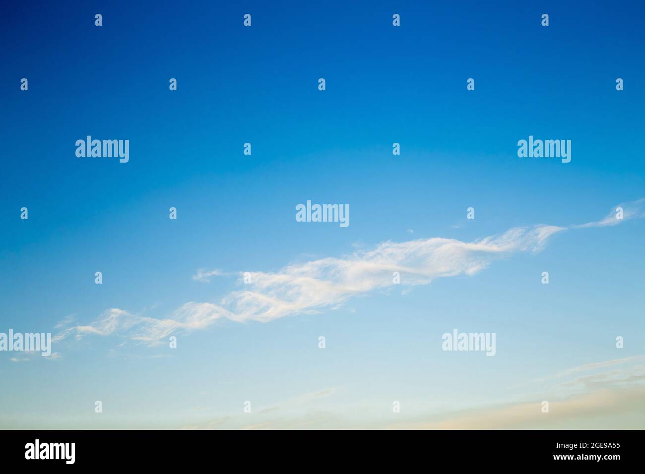 Beautiful blue sky with a white cloud in the form of a DNA helix. Sky panorama for screensavers, postcards, calendar, presentations. Warm summer day. Stock Photo