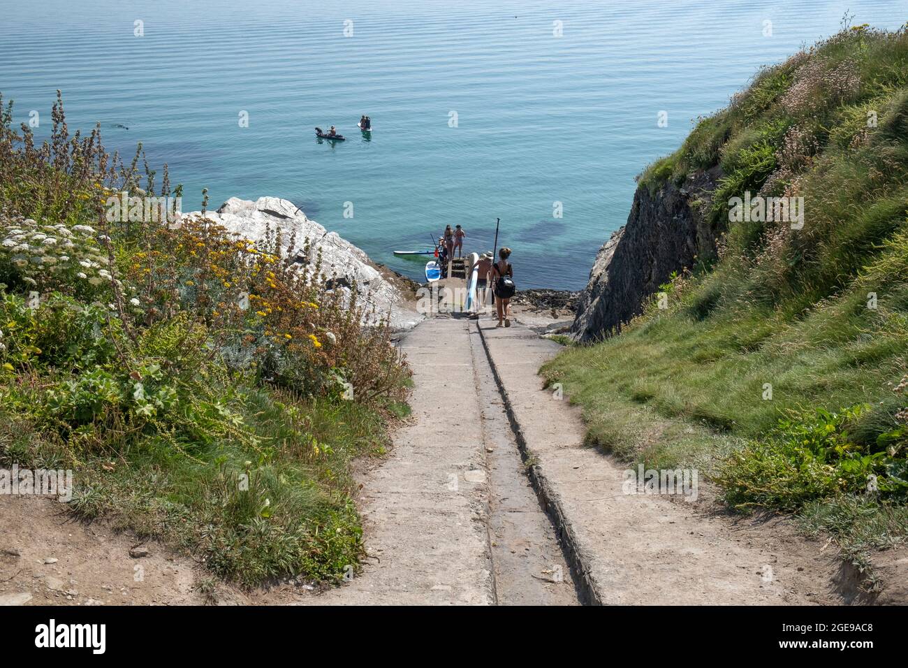 Holidaymakers launching their Stand Up Paddleboards from the old historic lifeboat slipway on Towan Head in Newquay in Cornwall. Stock Photo