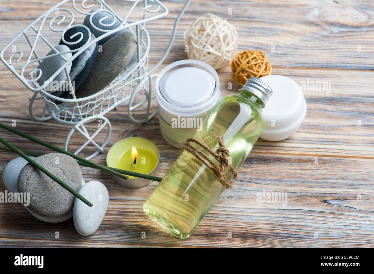 Aroma sticks, bueaty products, pebbles and lit candle in a SPA composition. Space for text Stock Photo