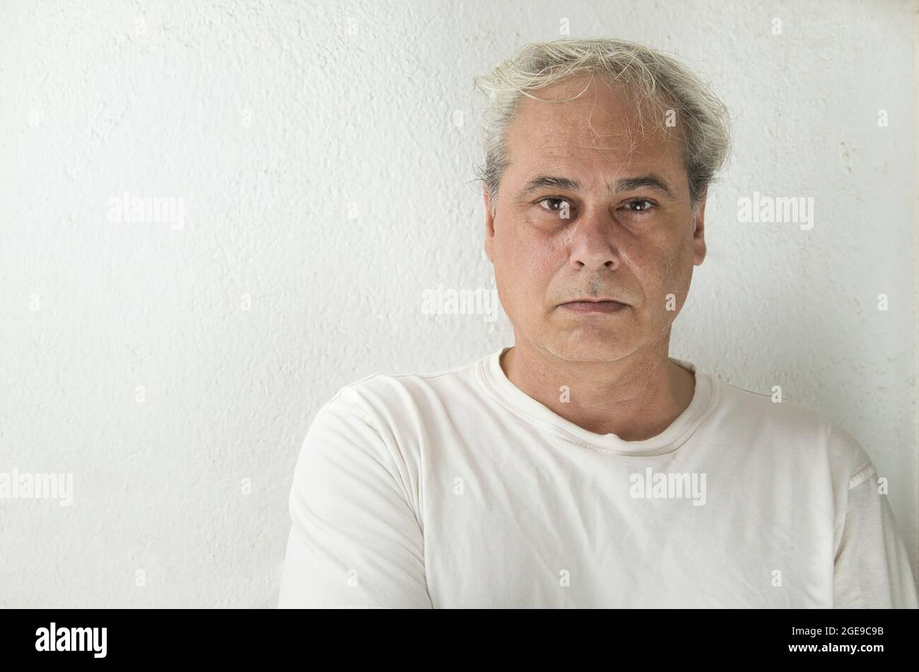 portrait of mature man with grey hair in white shirt on a white background Stock Photo