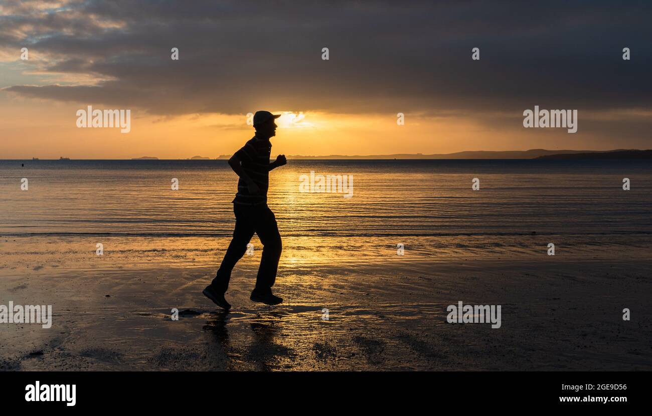 Silhouette of a man running on sandy beach at sunrise Stock Photo - Alamy