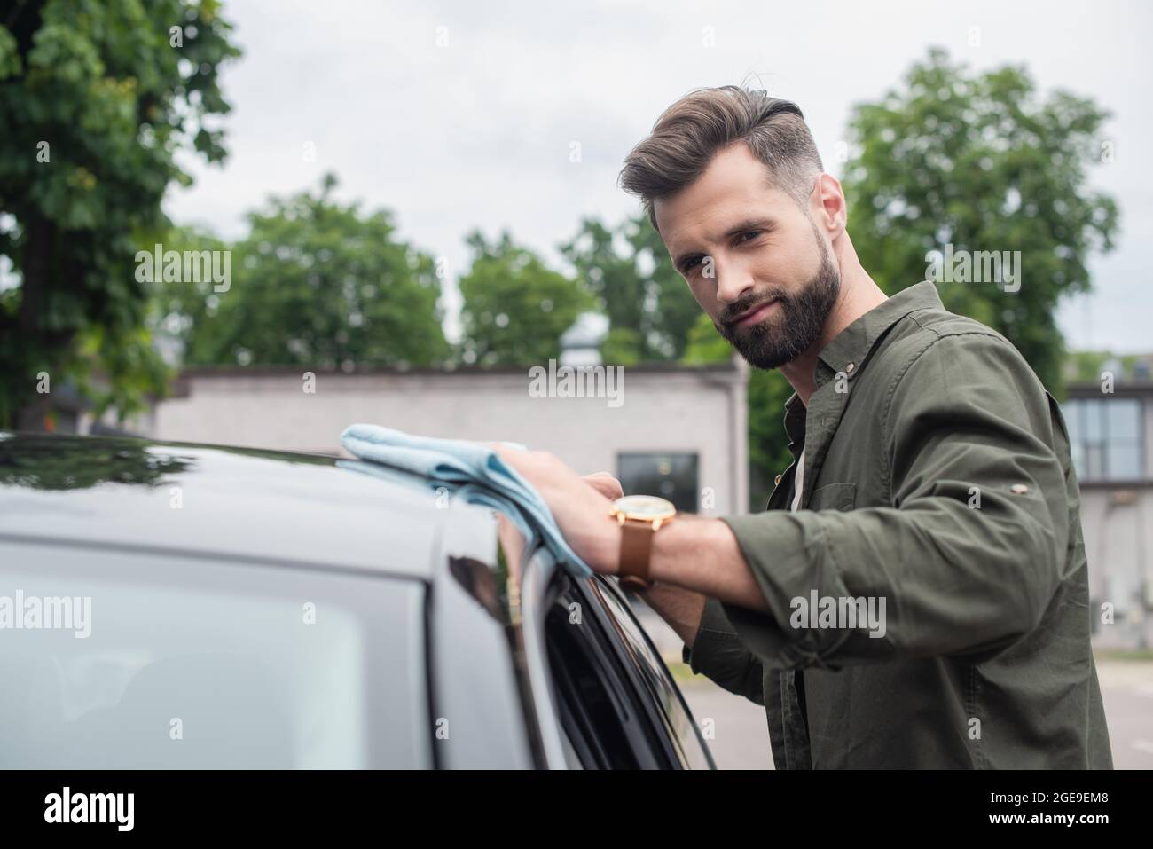 Bearded driver cleaning blurred car with rag outdoors Stock Photo - Alamy