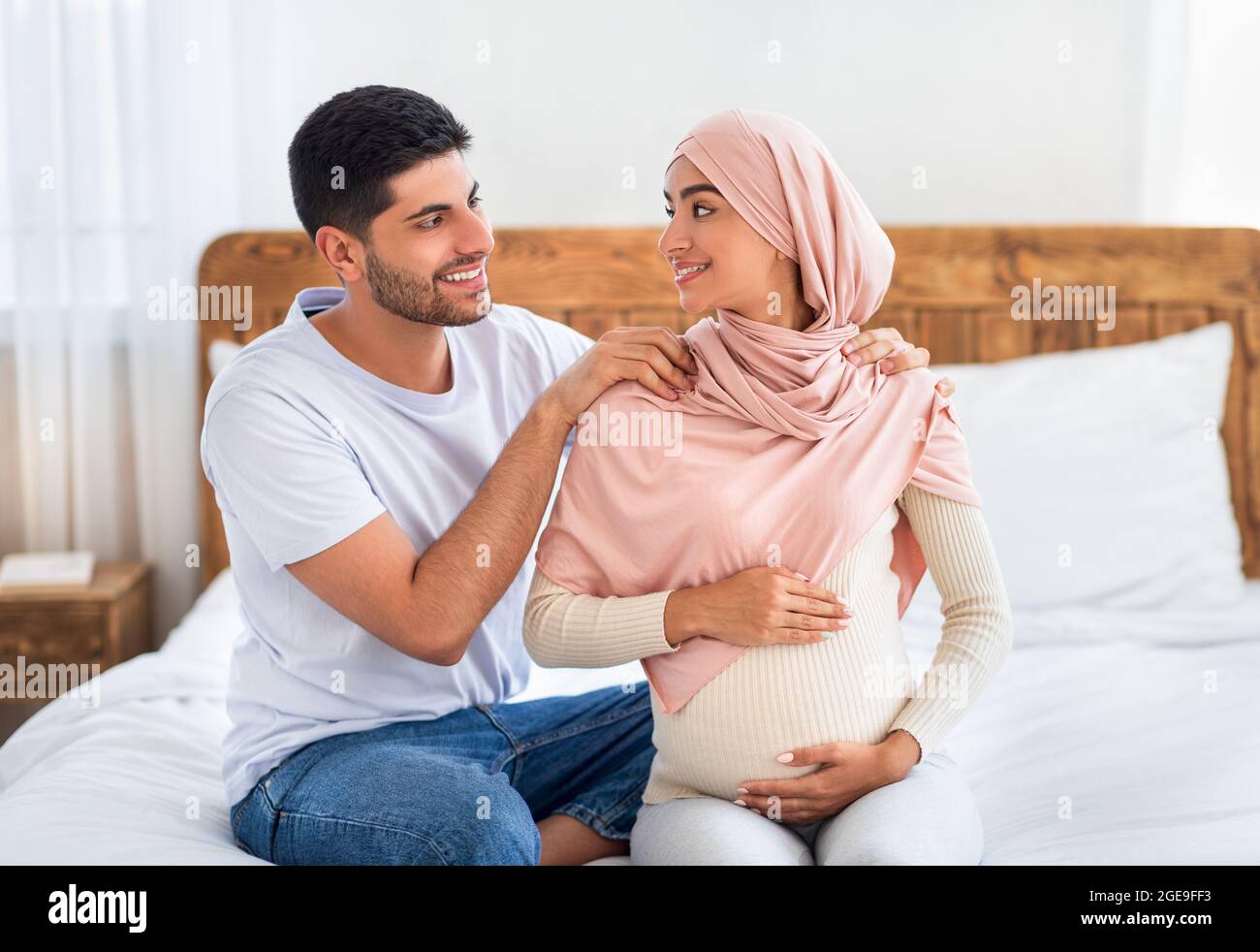 Pregnancy body massage. Caring muslim husband massaging shoulders of