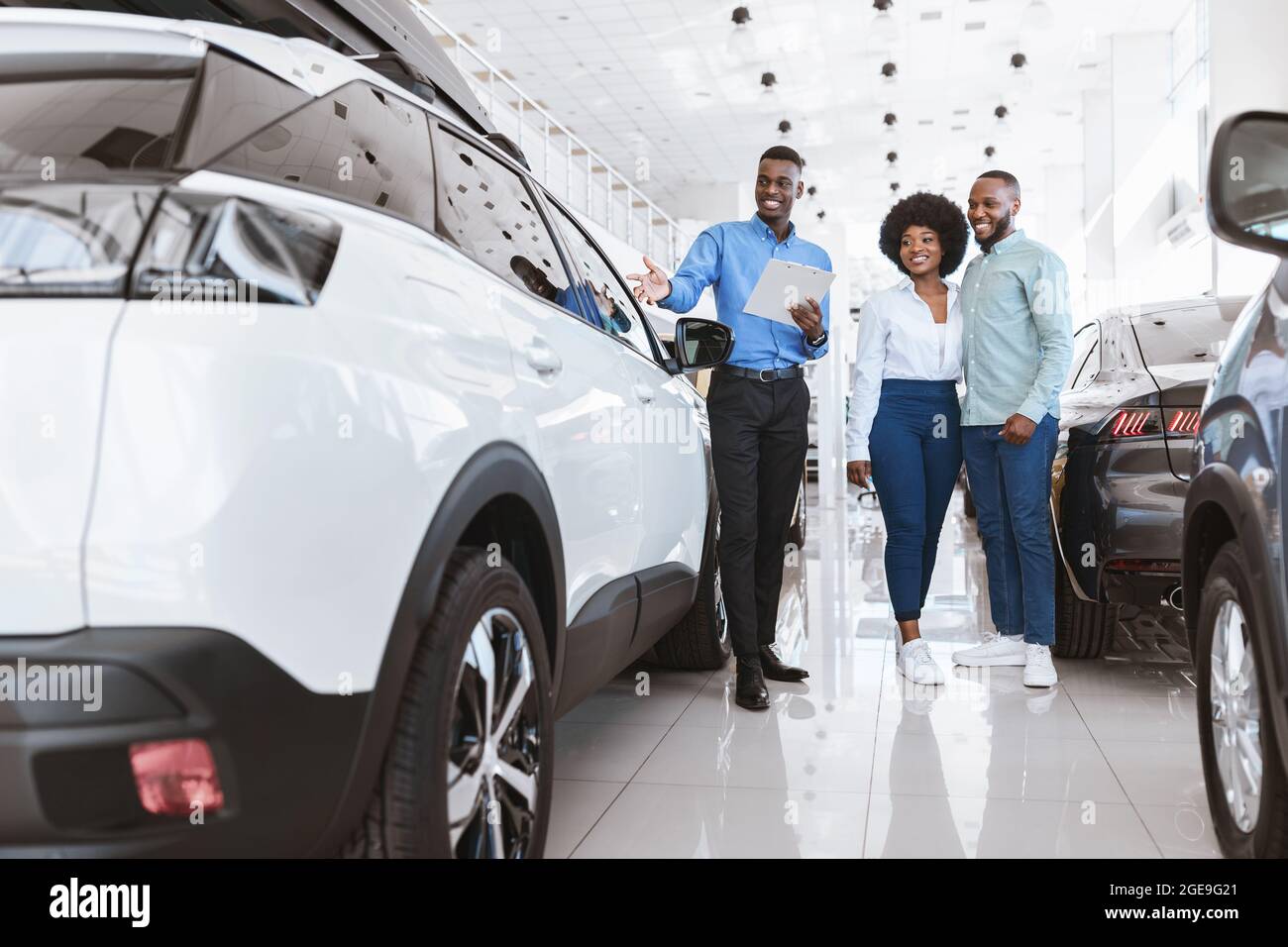 Happy young black couple buying new car together, speaking with ...