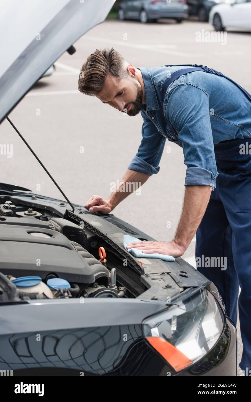 Mechanic holding rag and cleaning car with open hood outdoors Stock ...