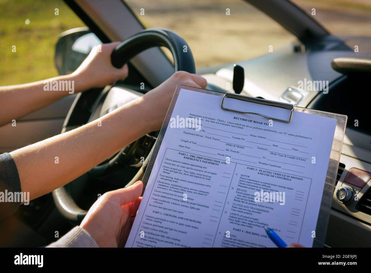 Examiner filling in driver's license road test form sitting with her