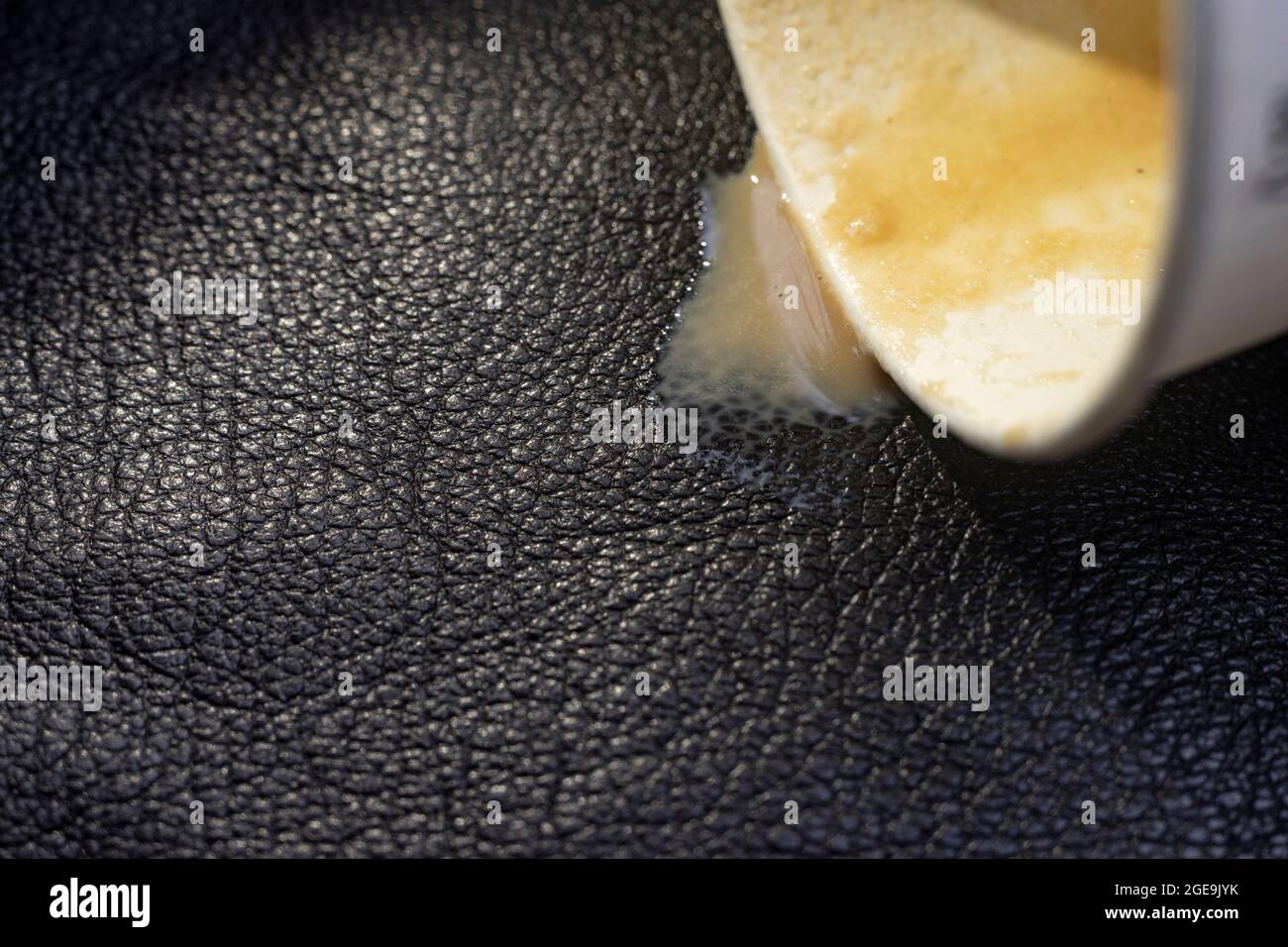 coffee spill from a paper cup, on black leather texture, cleaning