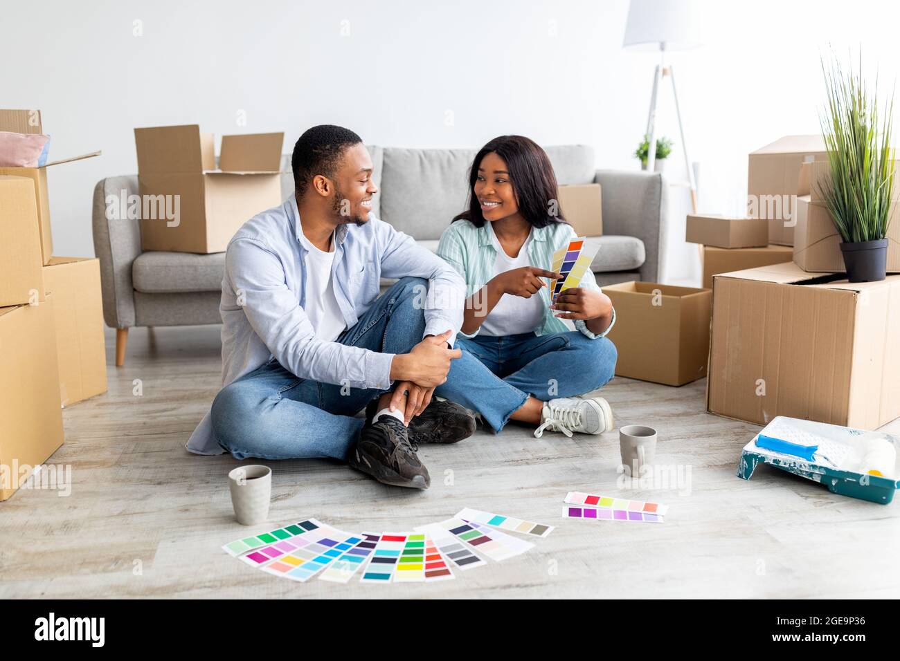 Creative african american spouses working on design for their house, discussing color palette while sitting among boxes Stock Photo