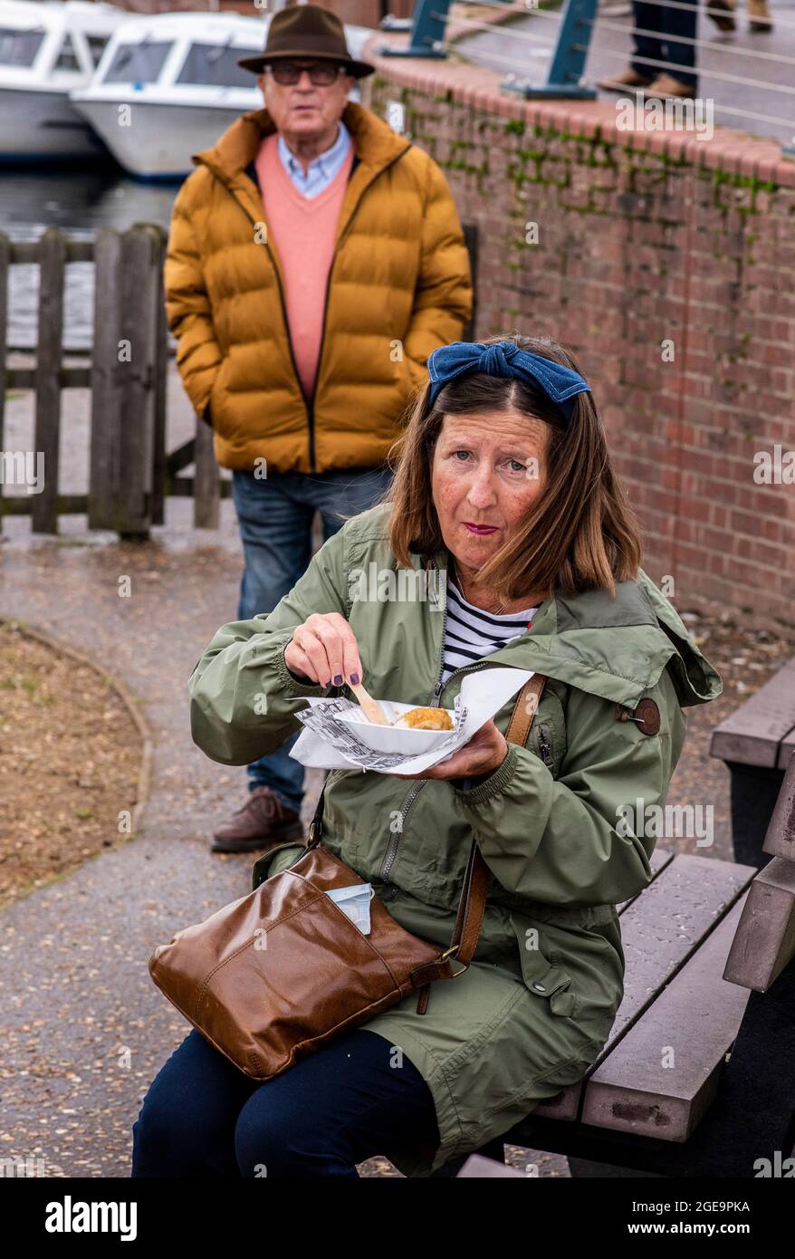 Woman eating fish and chips from carton in Norfolk in England. Stock Photo