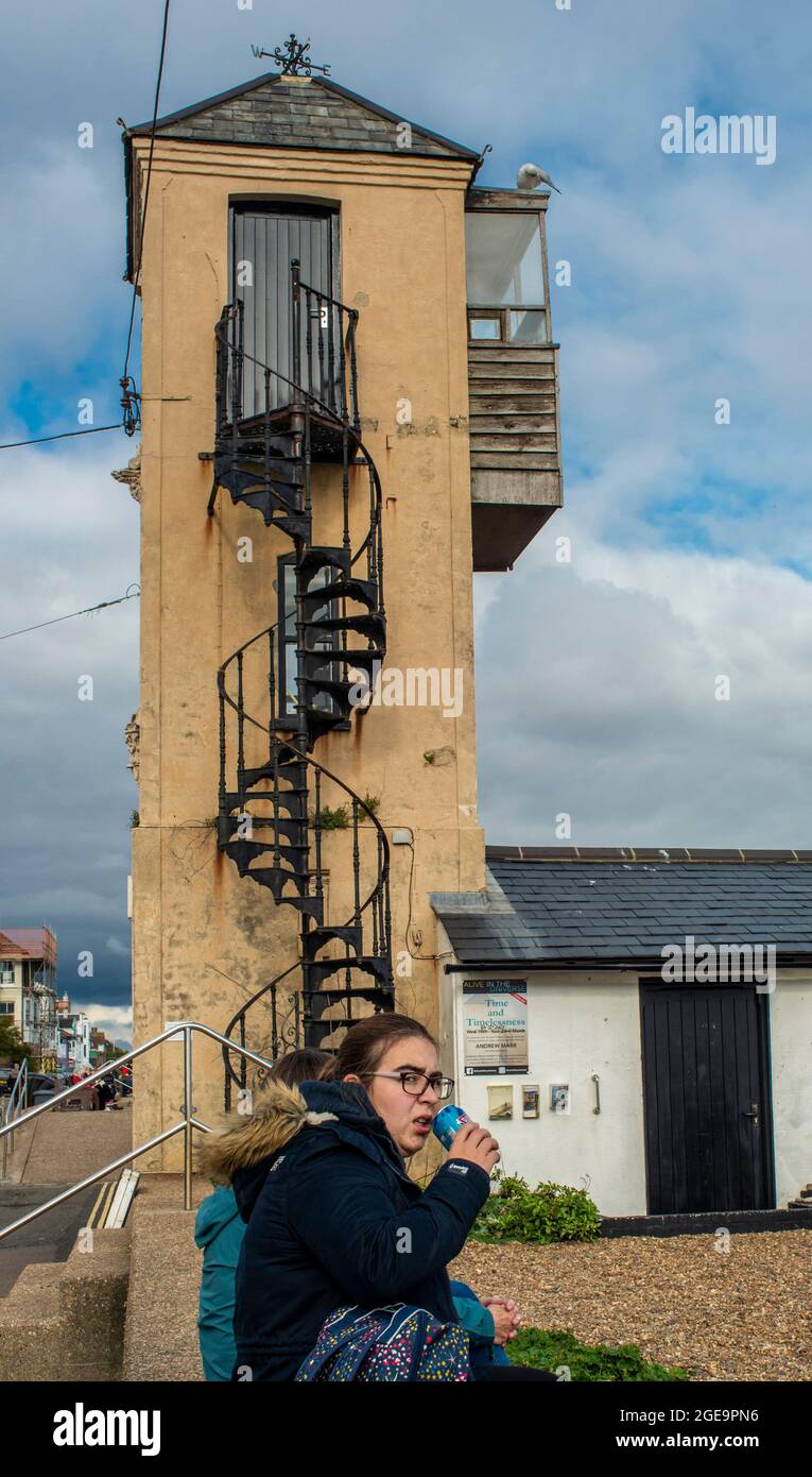 Woman sitting near tower with spiral staircase looking at camera and pulling a face in Southwold in England. Stock Photo
