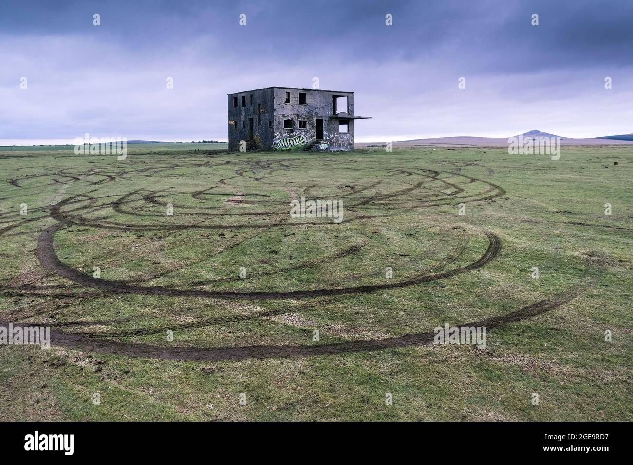 Vehicle tyre marks in the grass left by joy riders in front of the derelict control tower on the disused WW2 RAF Davidstow Airfield on Bodmin Moor in Cornwall. Stock Photo