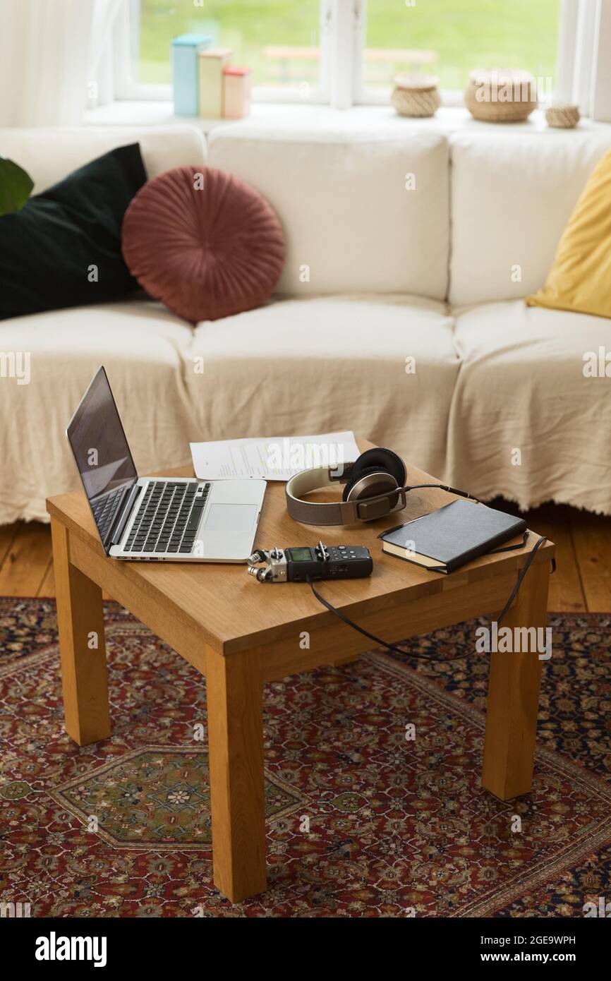 Audio recorder and headphones placed on wooden table with laptop and notebook for recording podcast at home Stock Photo