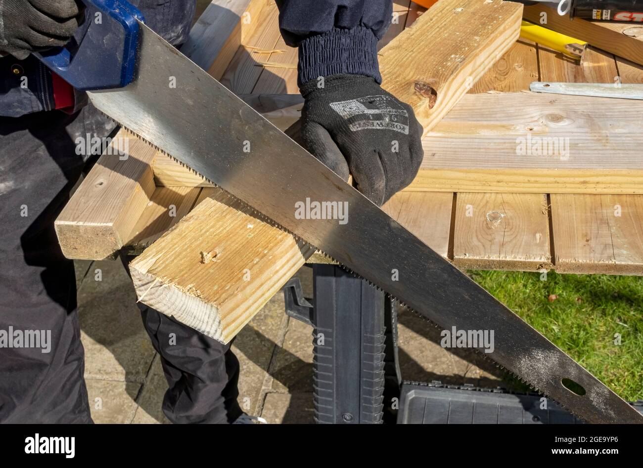 Close up of man using handsaw to cut piece of wood. Stock Photo