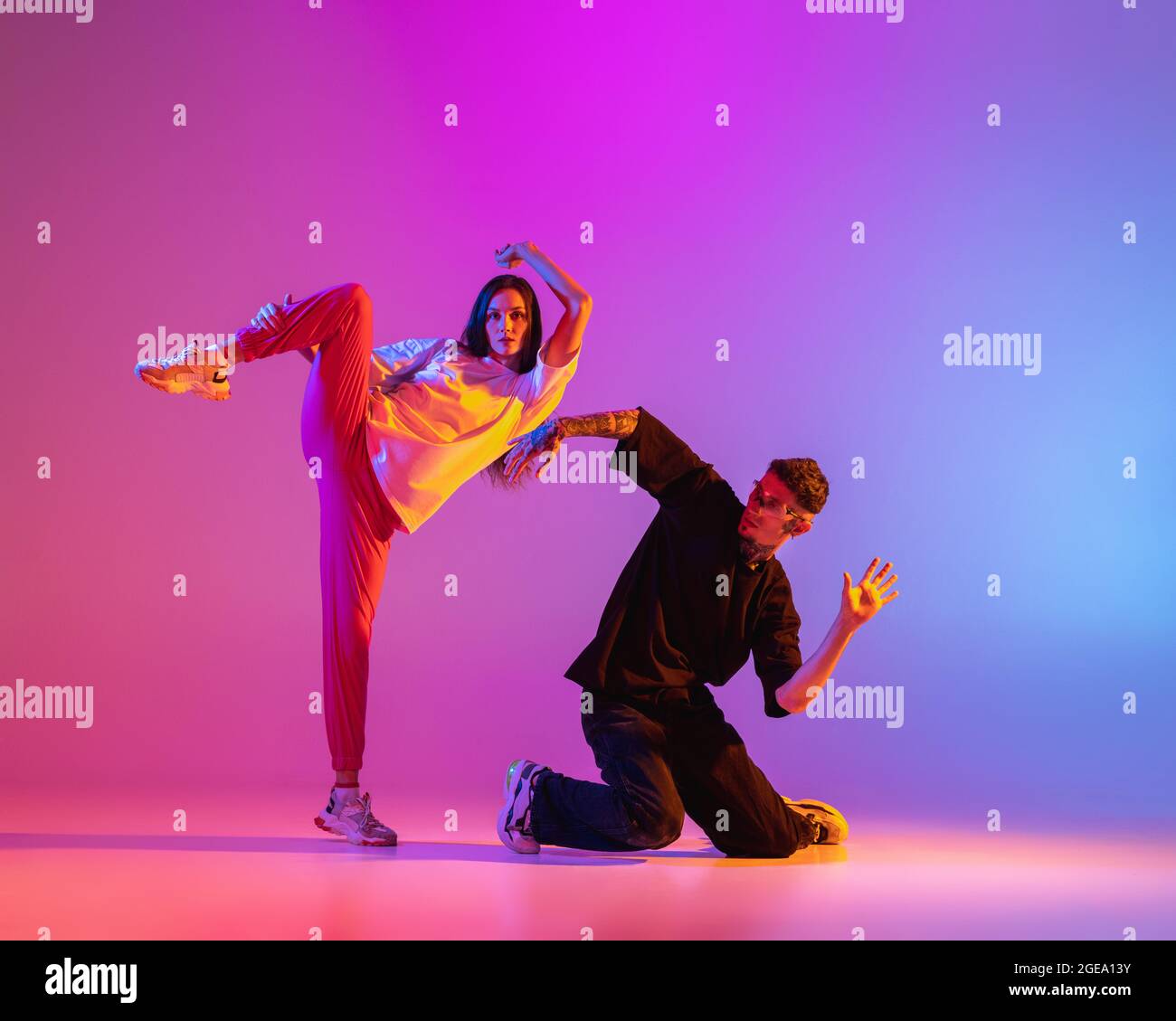 Two young people, guy and girl in casual clothes dancing contemporary dance,  hip-hop over pink background in neon light Stock Photo - Alamy