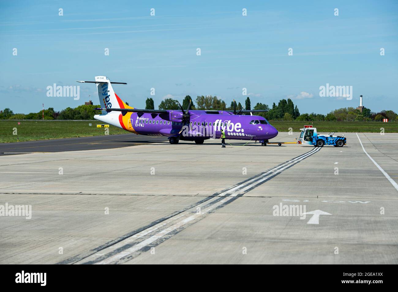 A Flybe aircraft is manoeuvred ready for take off by the ground crew. Stock Photo