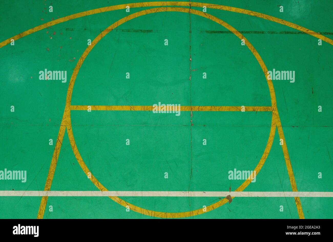 Green basketball court seen from above, with various marks of time, its