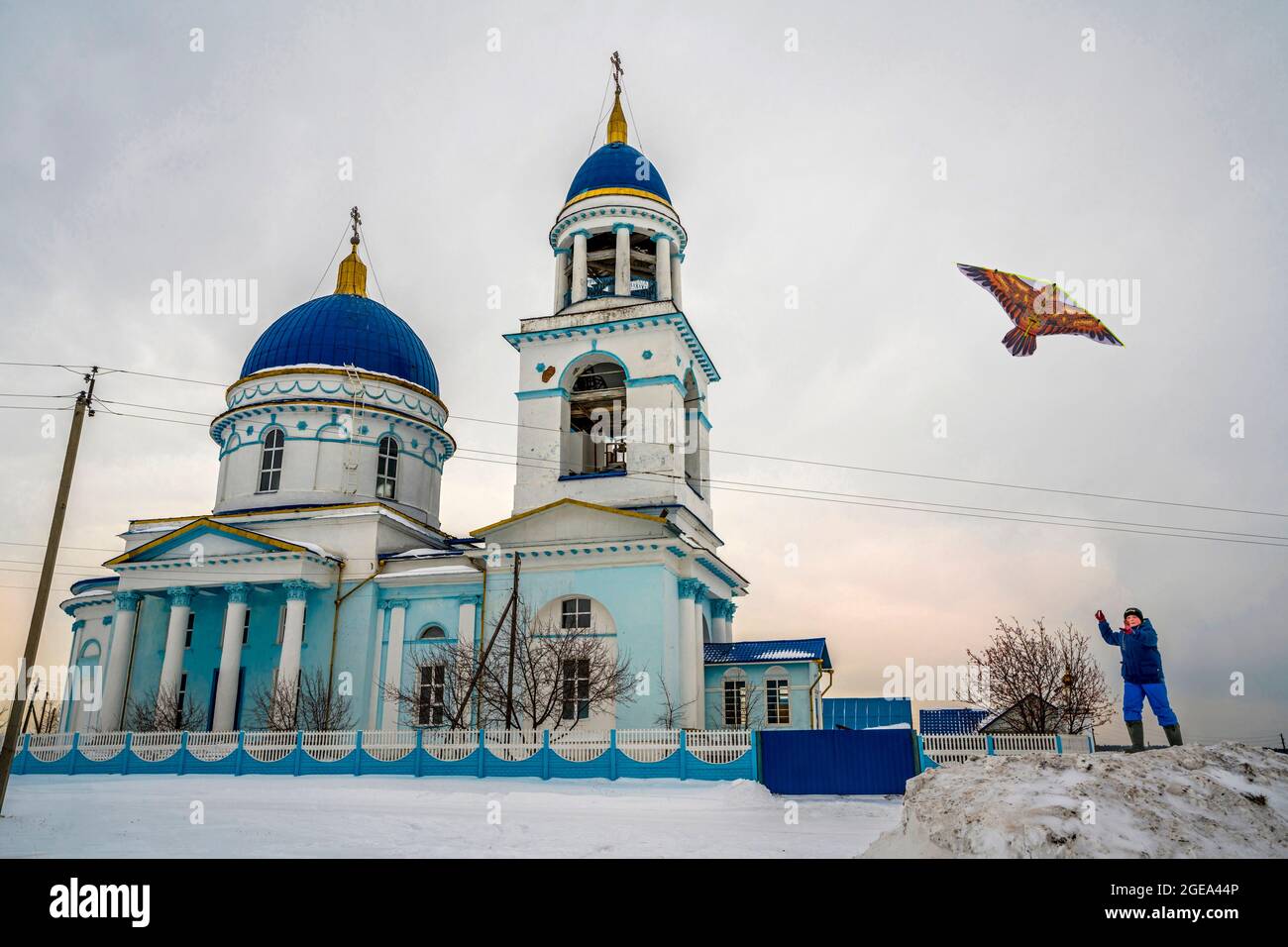 A boy flies a kite next to an Orthodox church in a small village of the Ural Mountains region in Russia. Stock Photo