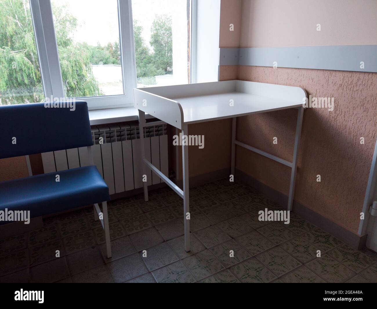 Diapers changing table on hardwood floor in hospital corridor. public