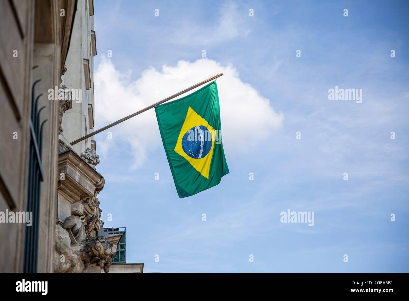 Brazilian flag displaying on a pole in front of the house against the blue sky. National flag of Brazil waving on a home hanging from a pole on a fron Stock Photo