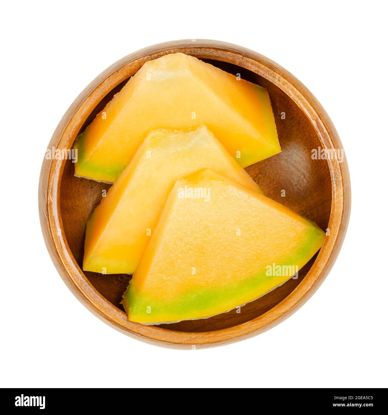 Honey Cantaloupe melon slices, in a wooden bowl. Triangular, ready-to-eat pieces of freshly cut, ripe fruit. Hybrid melon of species Cucumis melo. Stock Photo