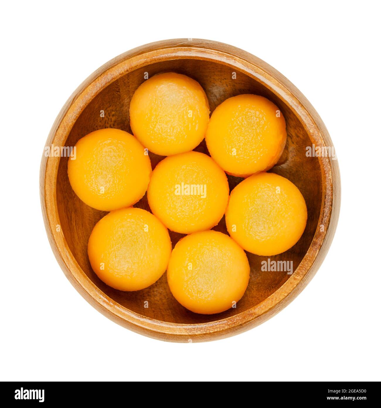 Honey Cantaloupe melon balls in a wooden bowl. Freshly cut out with a melon baller, ready-to-eat sweet spheres of a ripe fruit of a hybrid melon. Stock Photo