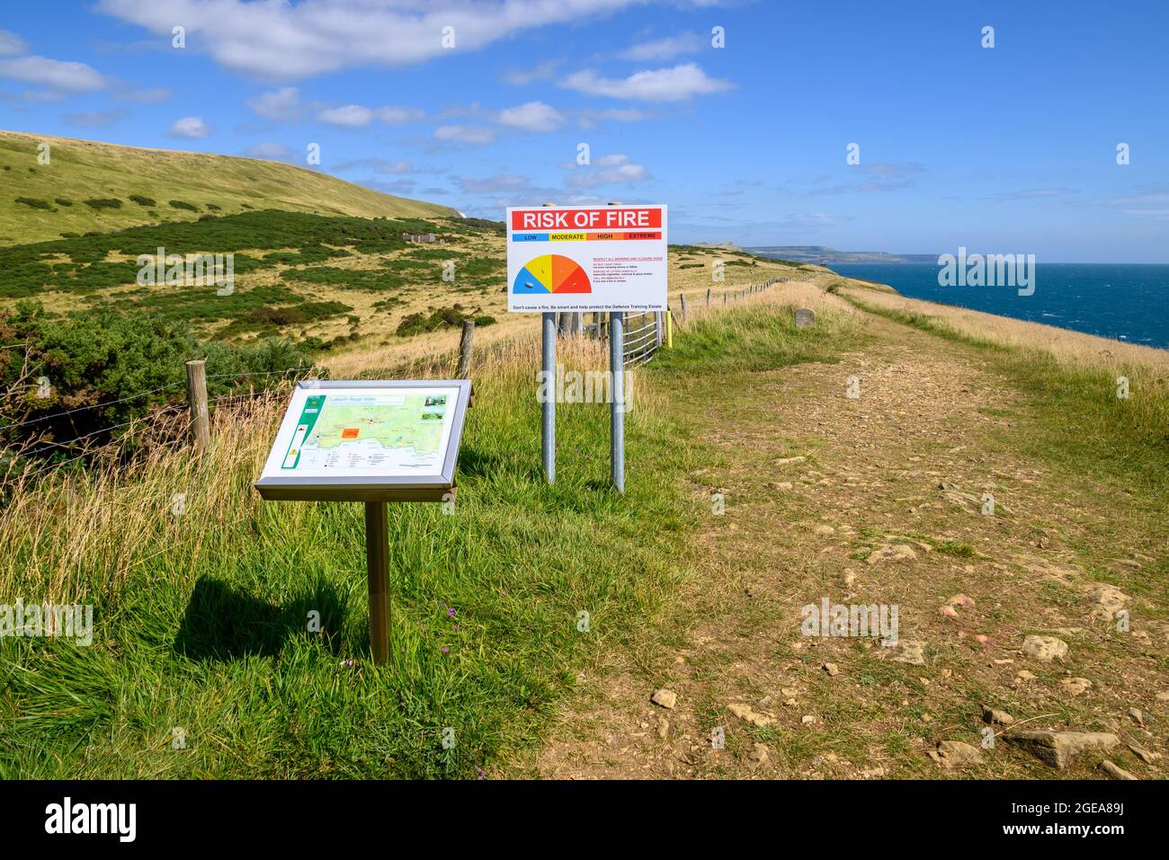 Route map and warning sign on the South West Coast Path to the east of Lulworth Cove, West Lulworth, Dorset, UK with an Army firing range on the left Stock Photo