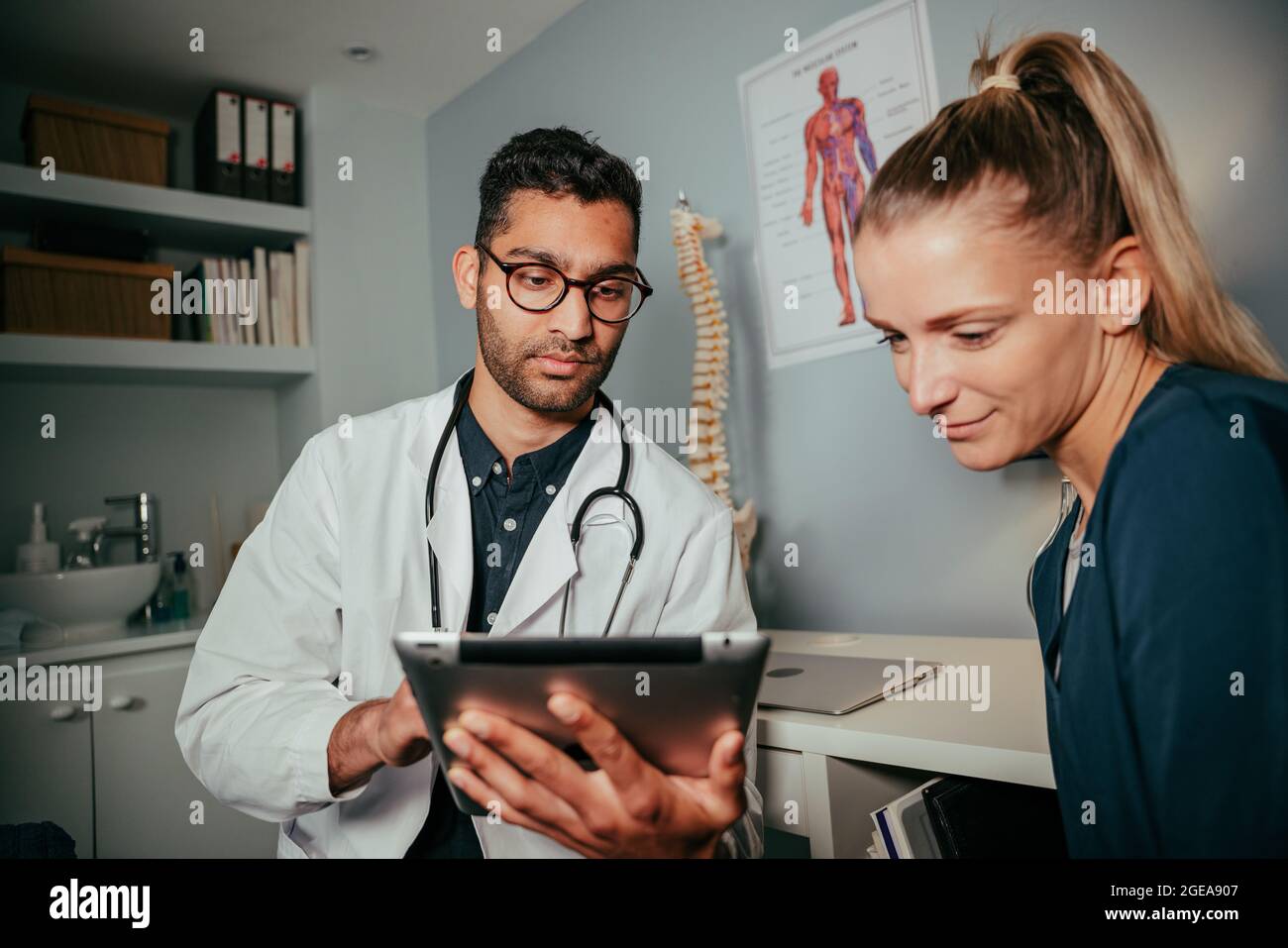 mixed race female nurse sitting with male doctor using digital tablet Stock Photo