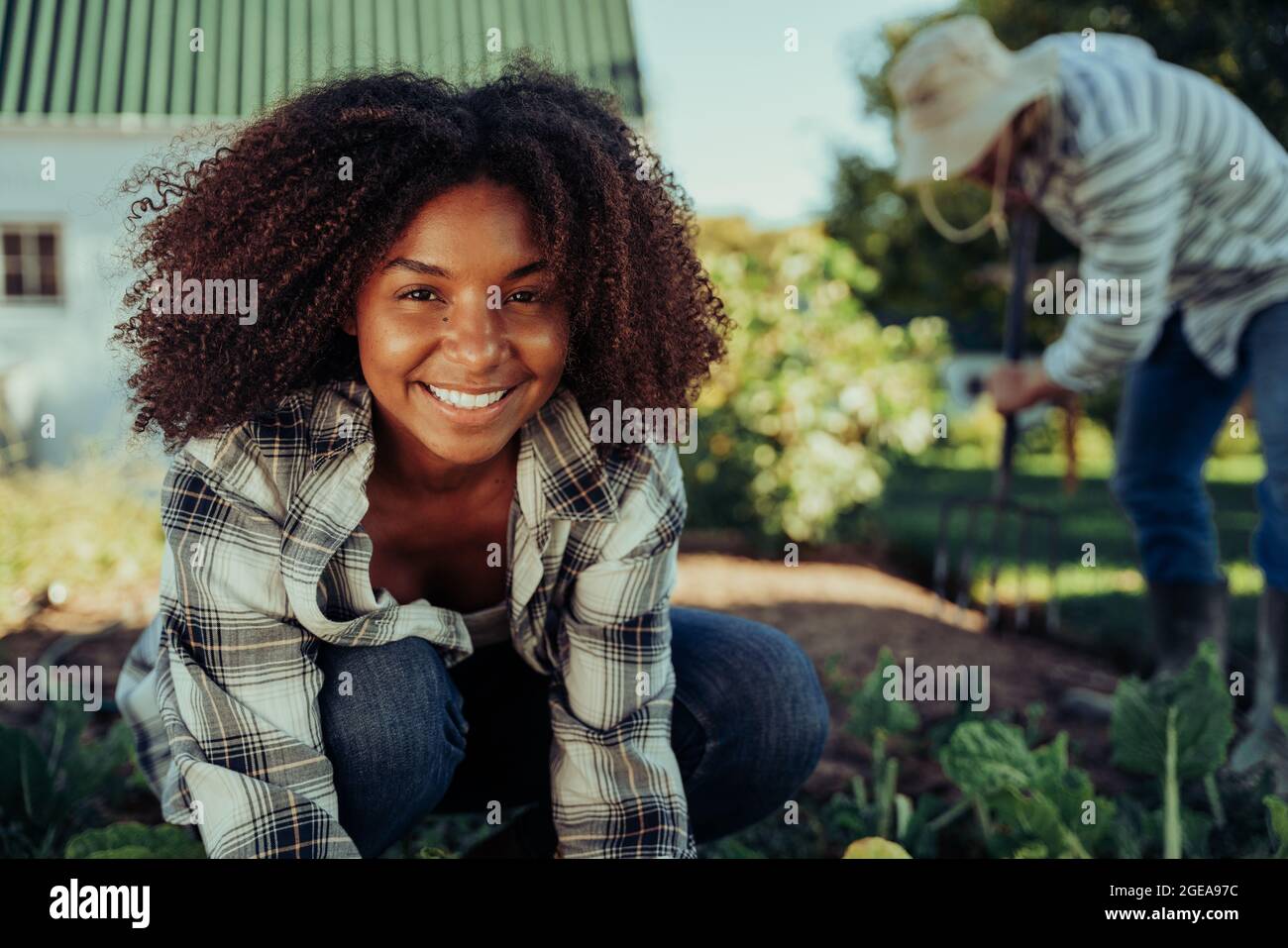 Beautiful smiling female farmer working in vegetable garden organising produce feeling active  Stock Photo