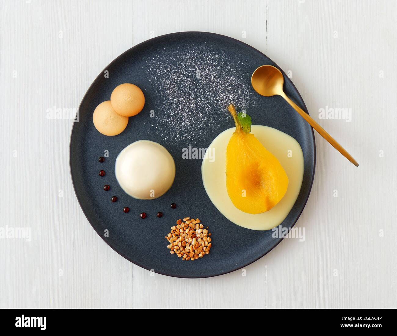 Panna cotta, traditional Italian dessert with muscat poached pears and creme Anglaise, crushed hazelnuts, caramel lentils and biscuits. High angle vie Stock Photo