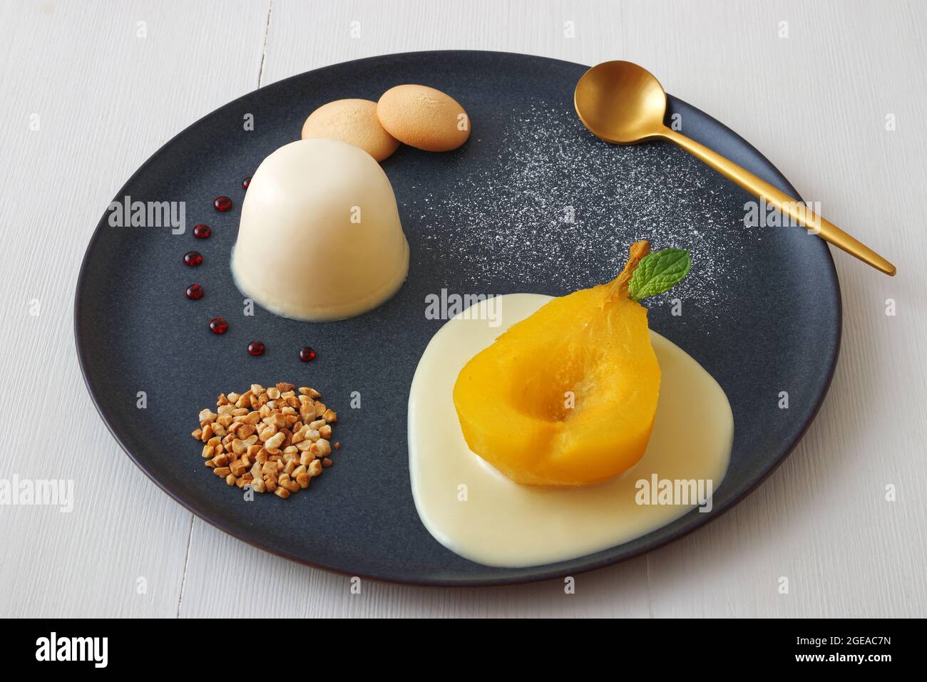Panna cotta, traditional Italian dessert with muscat poached pears and creme Anglaise, crushed hazelnuts, caramel lentils and biscuits. High angle vie Stock Photo
