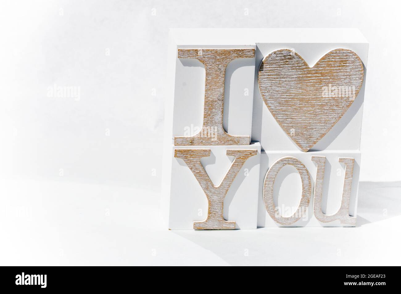 I Love You phrase set on a white tile. The image is against a white background and is mostly white with the writing in pale brown/biscuit colour Stock Photo