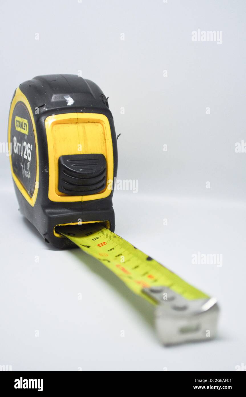 A black and yellow tape measure set against a white background Stock Photo