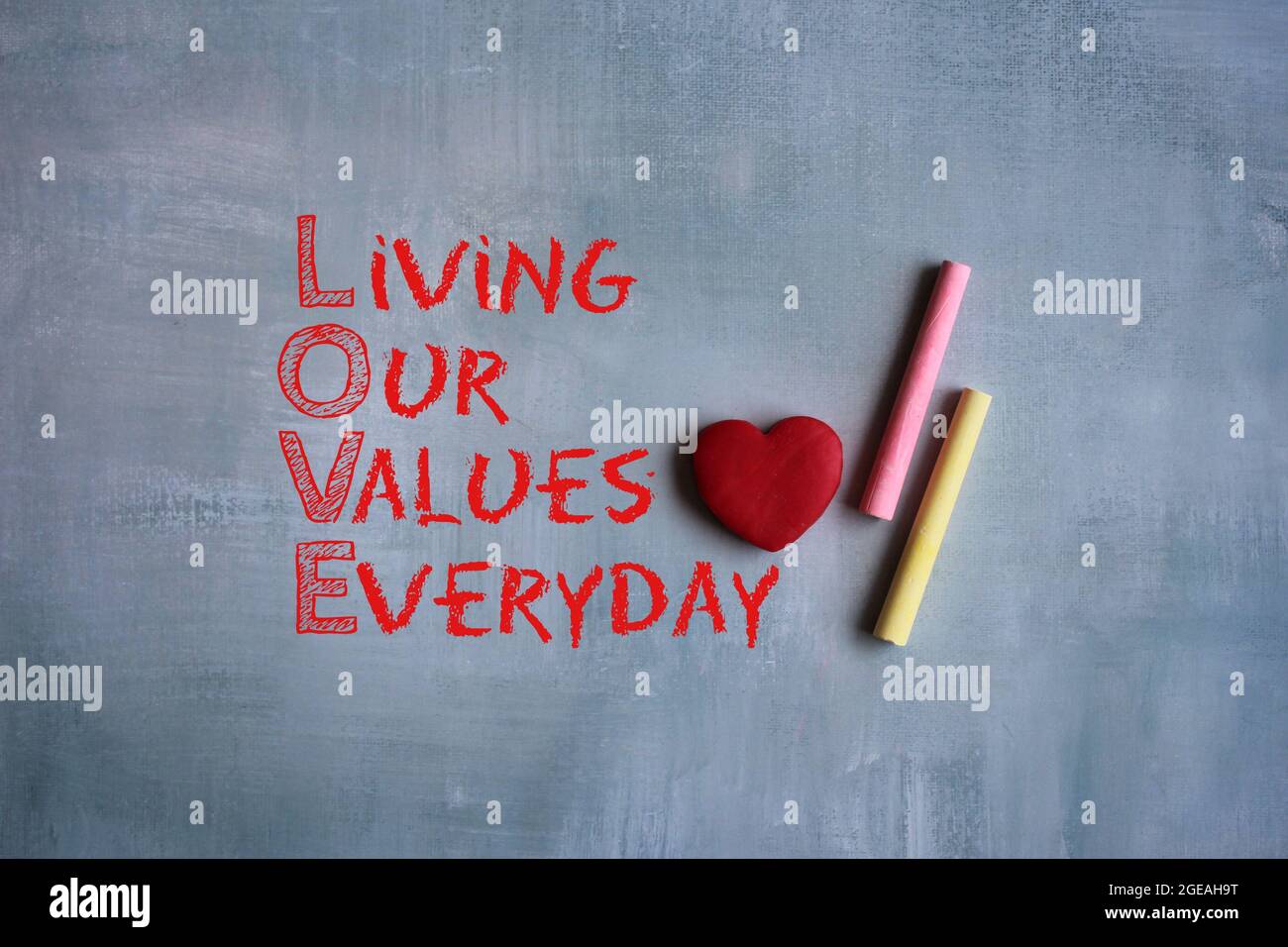 LOVE acronym - Living our values everyday, chalkboard and red heart on concrete cement Stock Photo