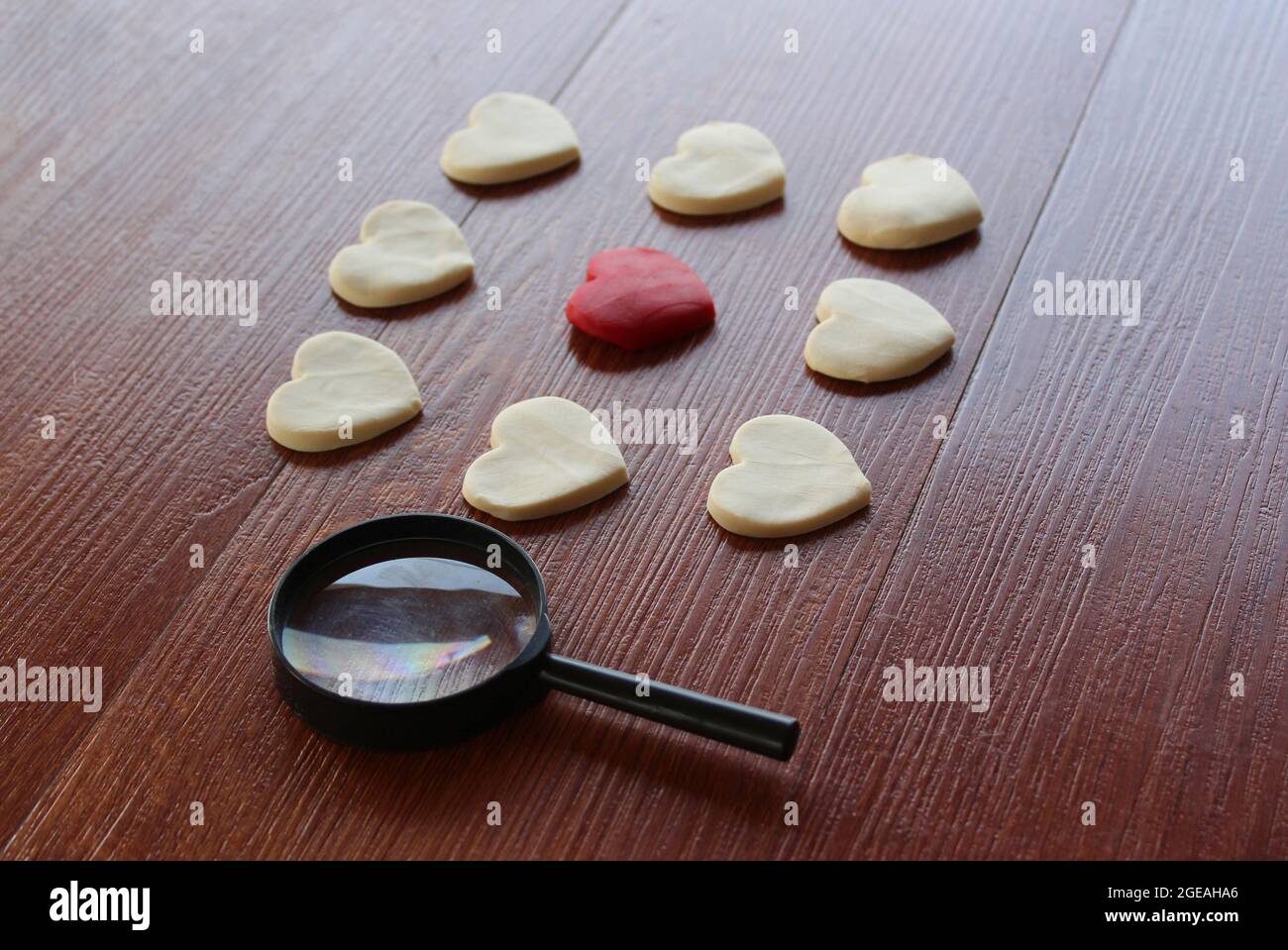 Magnifying glass, red heart and white heart. Finding true love valentine concept. Stock Photo