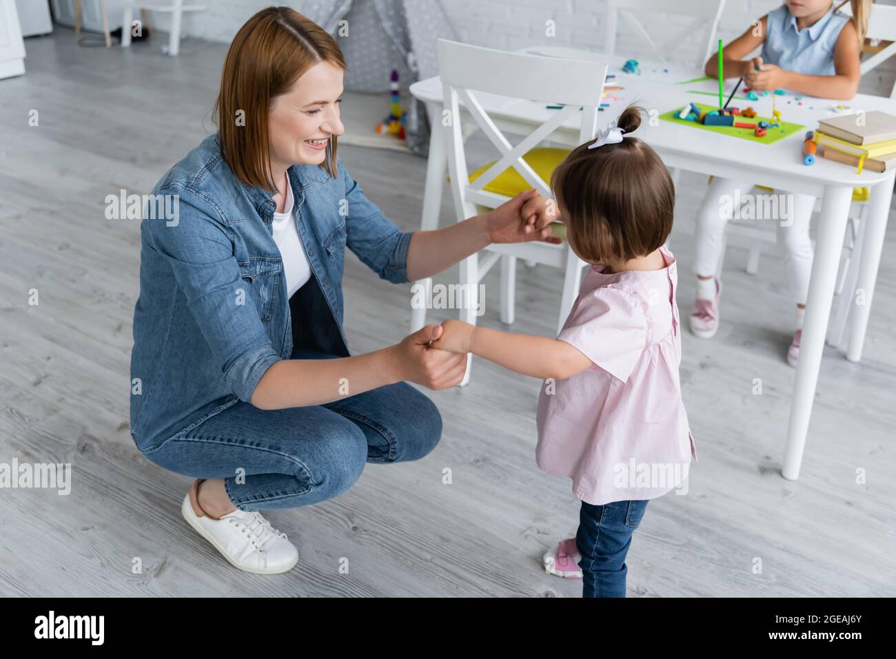 Happy Kindergarten Teacher Holding Hands With Disabled Kid Near happy-kindergarten-teacher-holding-hands-with-disabled-kid-near