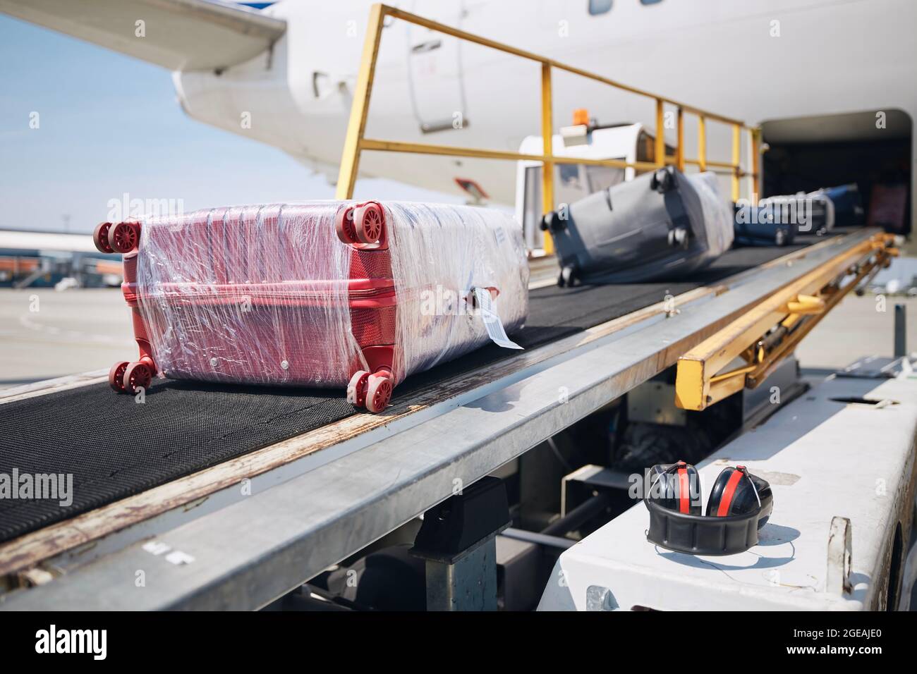 Loading of luggage to airplane. Suitcases on conveyor belt to plane. Stock Photo