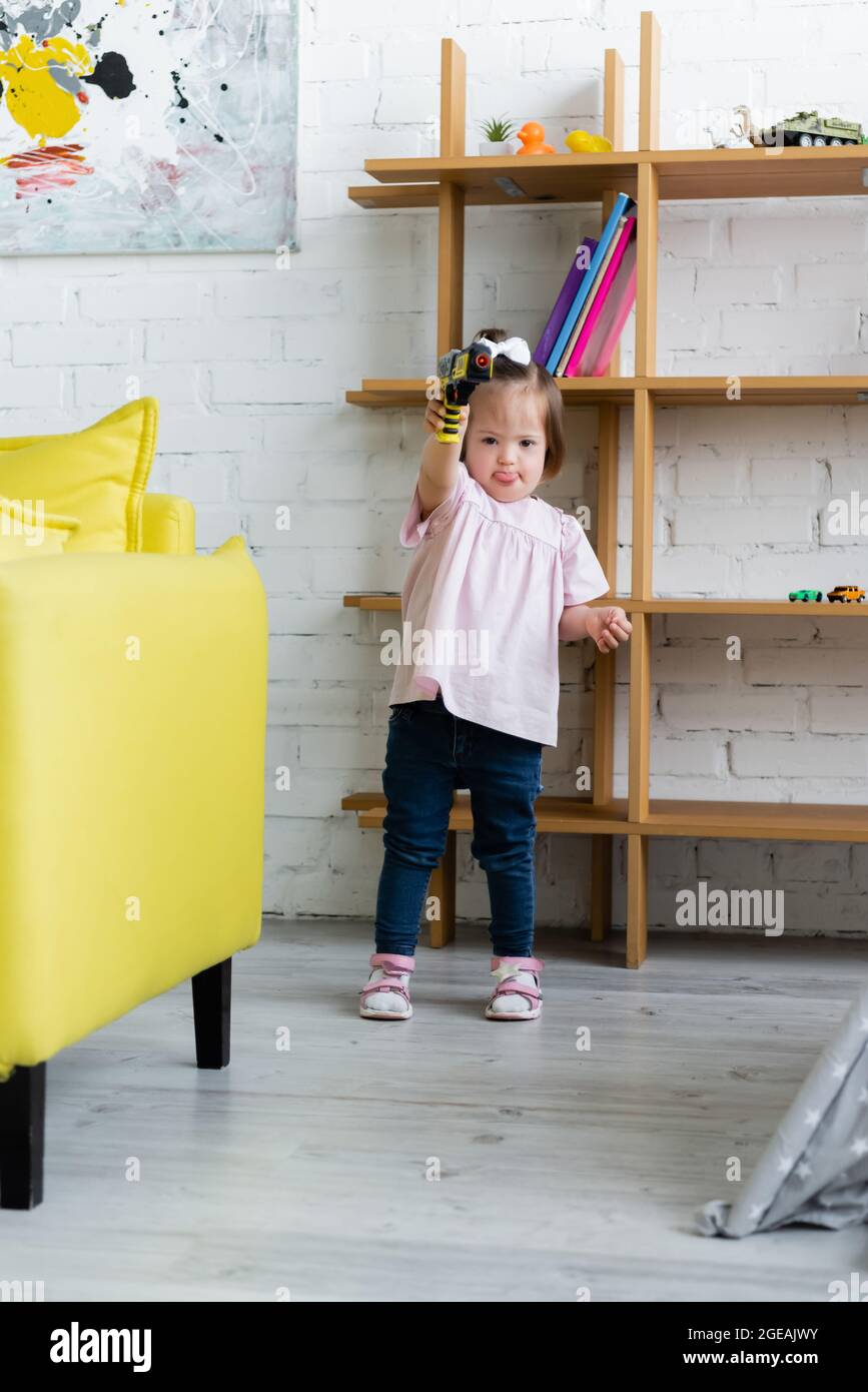 kid with down syndrome holding toy gun in playroom Stock Photo - Alamy