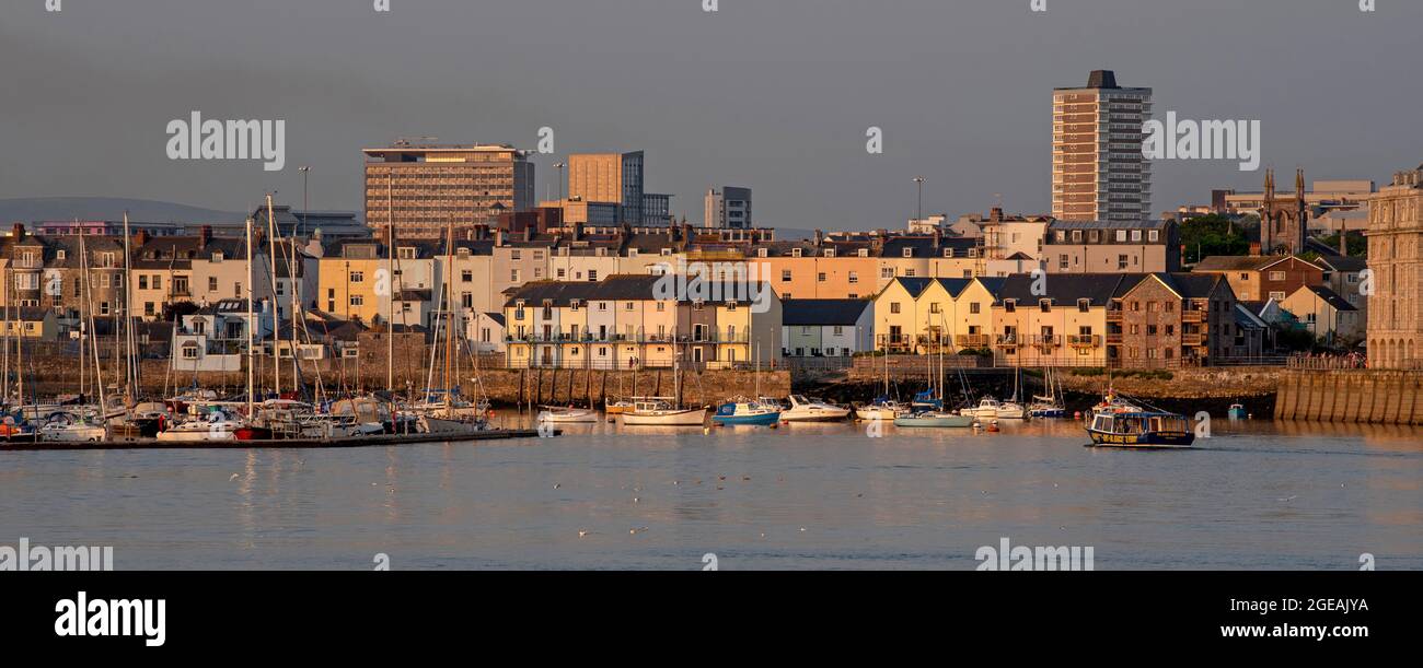 Plymouth, Devon, England, UK. 2021. Waterfront homes on the River Tamar, Plymouth. Evening light,  backdrop the high rise buildings of the city centre Stock Photo
