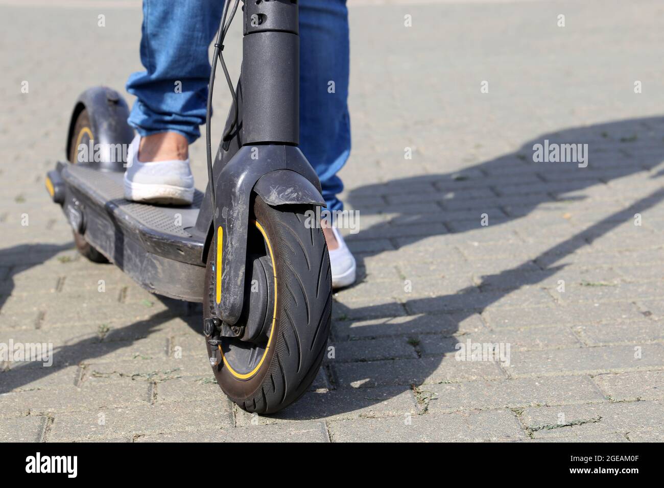 Girl in jeans rides an electric scooter on a city street, female legs on  sidewalk. Riding e-scooter in summer Stock Photo - Alamy