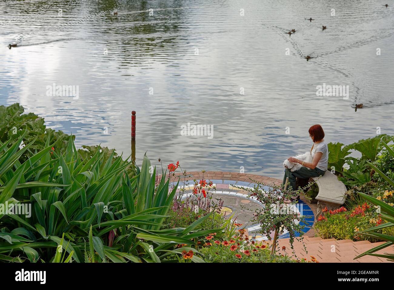 Turtle Lake; woman sitting petting white dog, relaxing, water, flowers