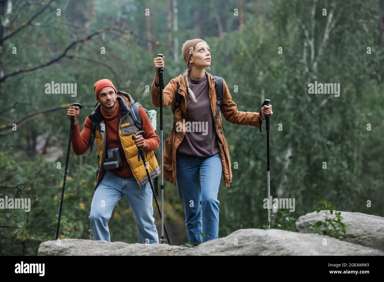 couple trekking with hiking sticks in forest Stock Photo