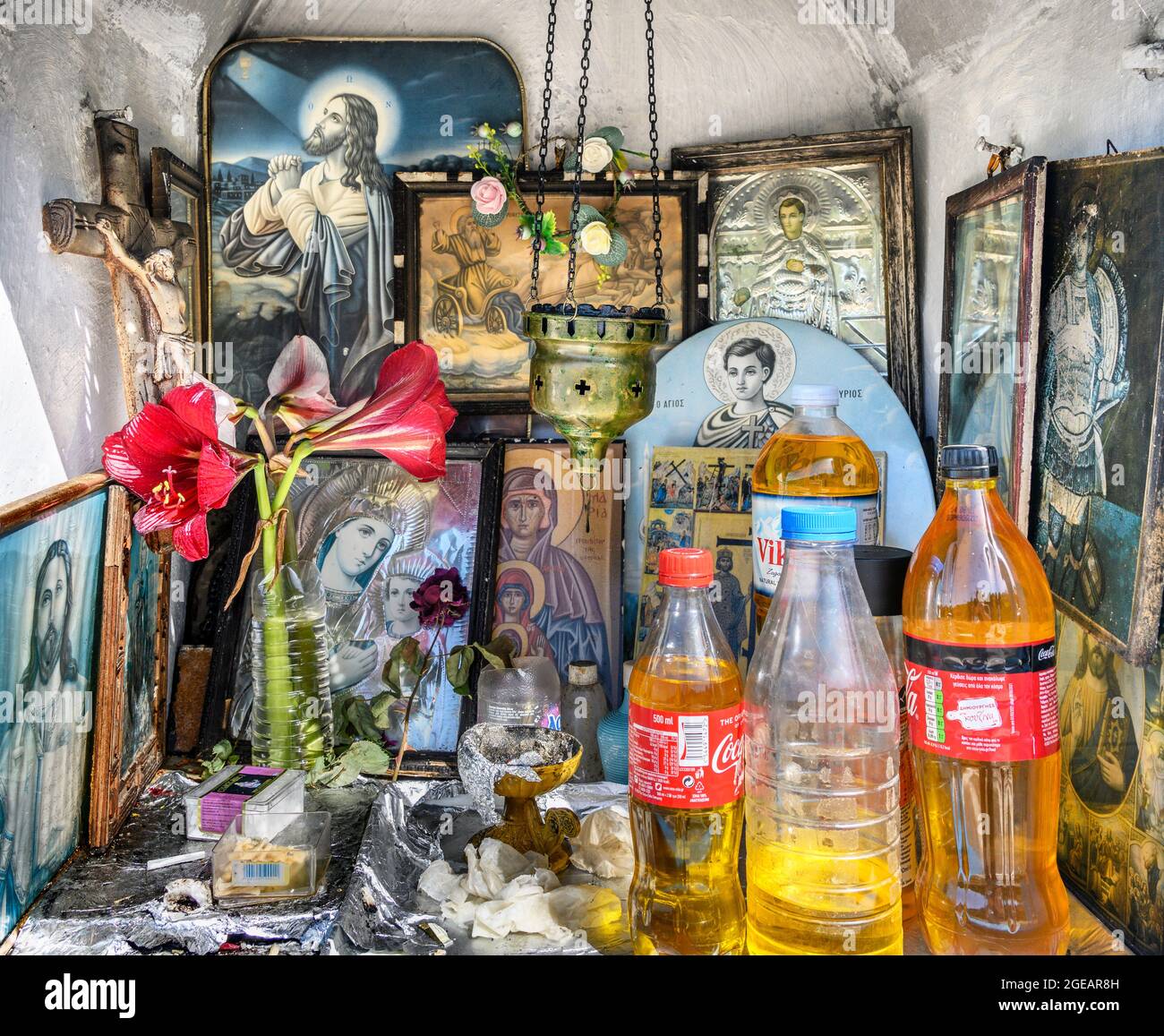 The interior of a, Greek Orthodox, roadside shrine displaying religious icons, bottles of holy oil and incense burners.   Arcadia, Peloponnese, Greece Stock Photo