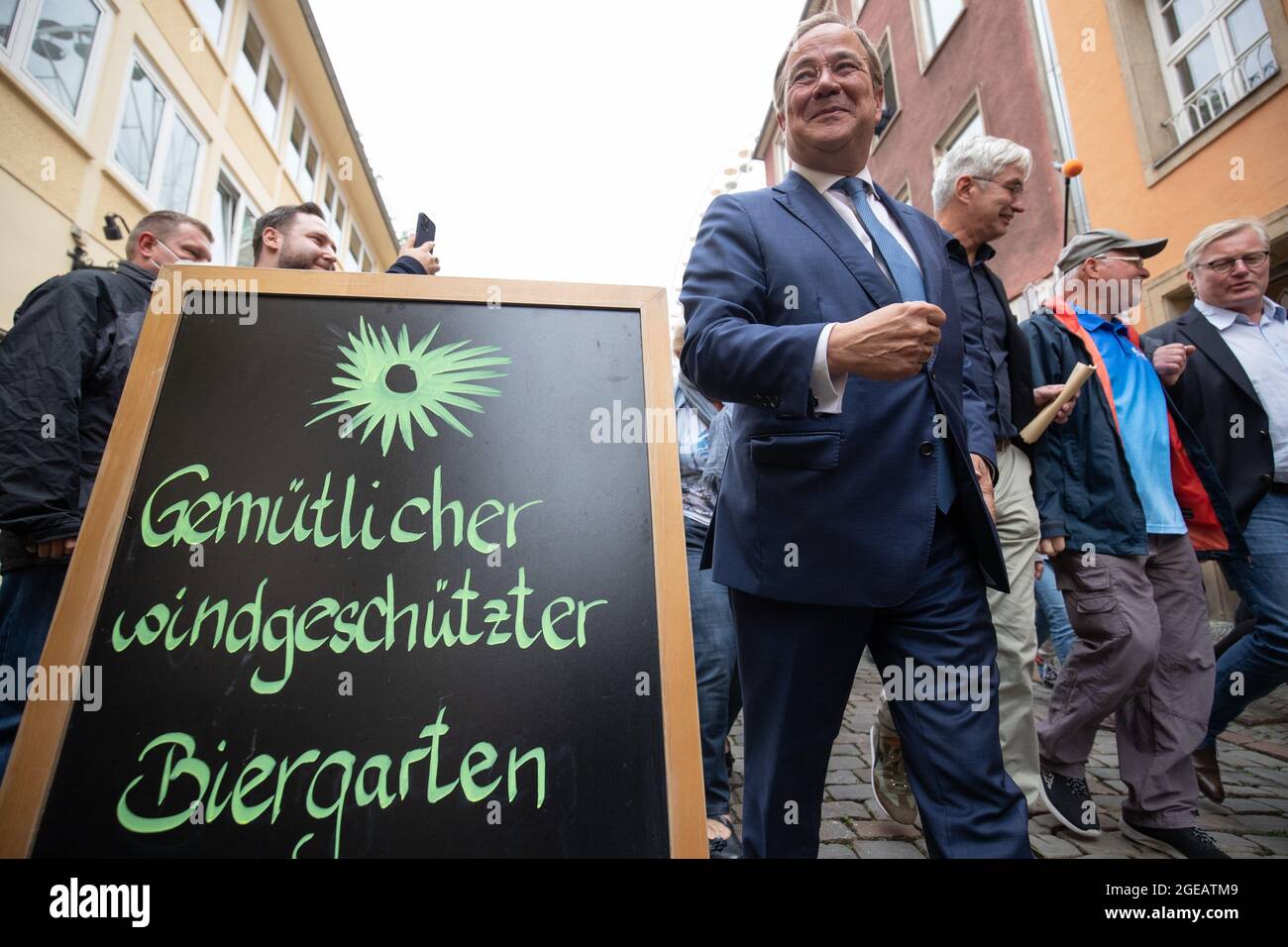 18 August 2021, Lower Saxony, Osnabrück: Armin Laschet, candidate for chancellor of the CDU/CSU and chairman of the CDU, walks past a sign saying 'Cosy beer garden sheltered from the wind' as part of his campaign tour through Osnabrück's old town. Photo: Friso Gentsch/dpa Stock Photo