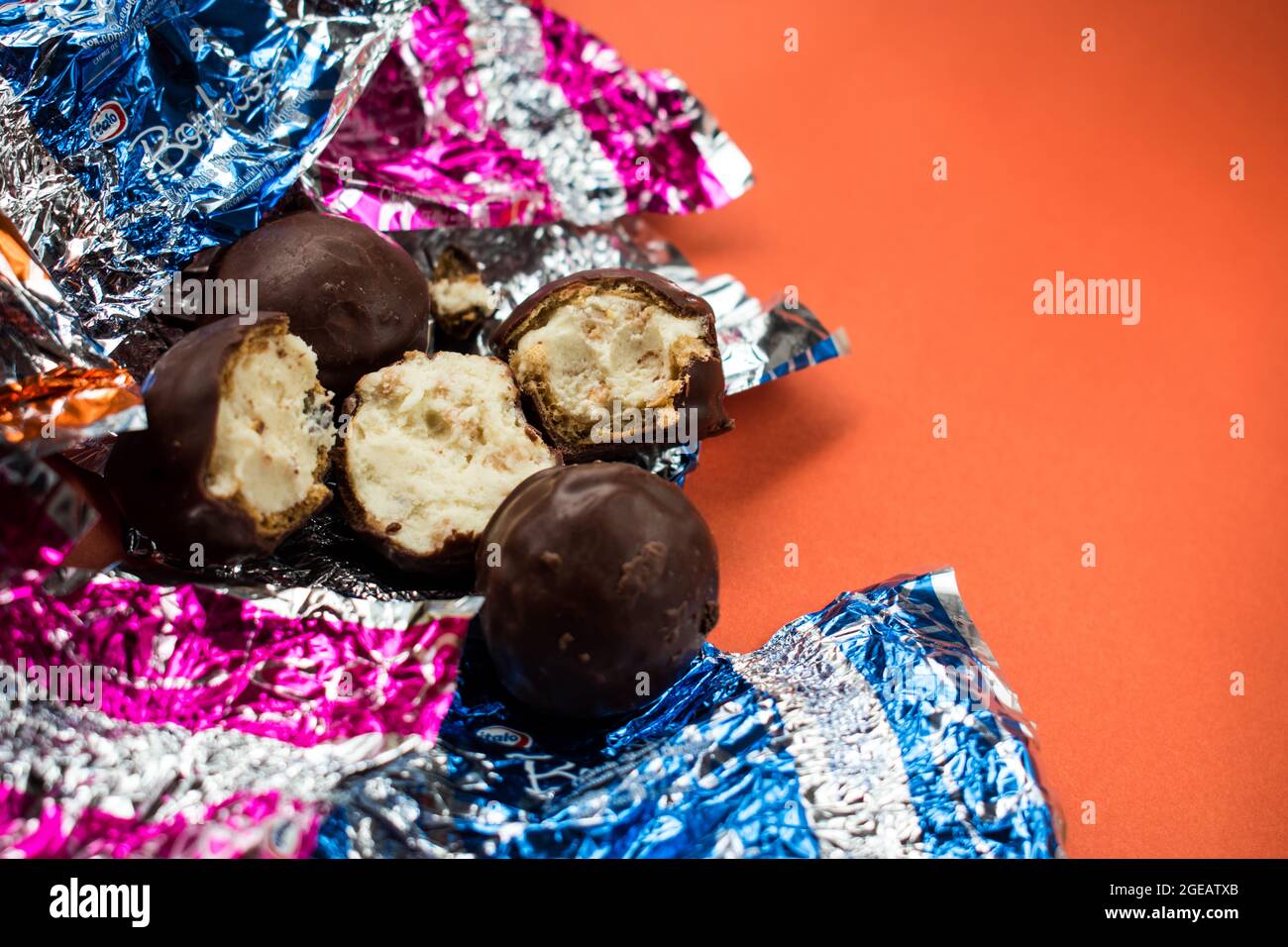 Some chocolates and some different colorful wrappers on orange surface Stock Photo