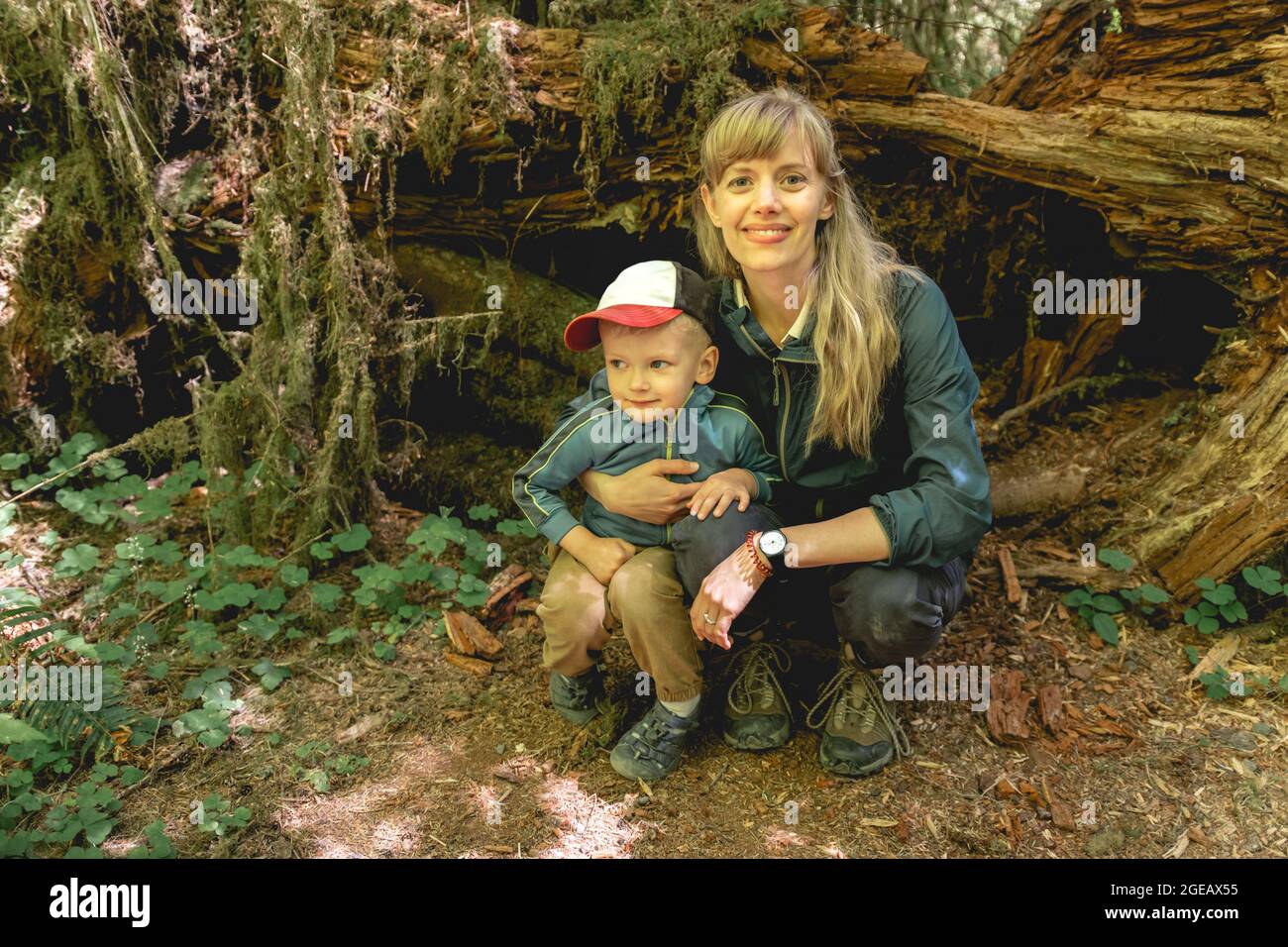 Mother and son crouching on a hike in the Hoh Rainforest in Olympic National Park. Stock Photo
